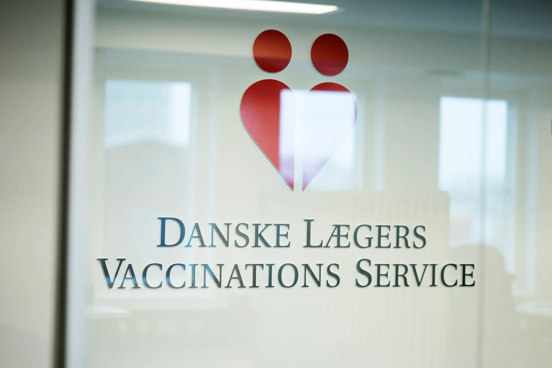 Danske Lægers Vaccinations Service logo på kontorvæg